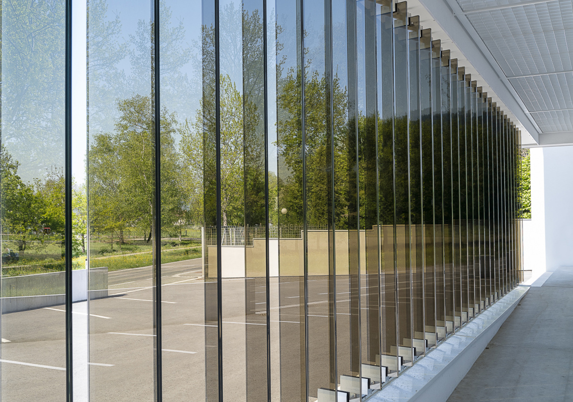 Die Verschattung der Fensterflächen erfolgt durch vertikale Glaslamellen, die je nach Anforderung verstellbar oder in fixer Ausrichtung justiert sind.