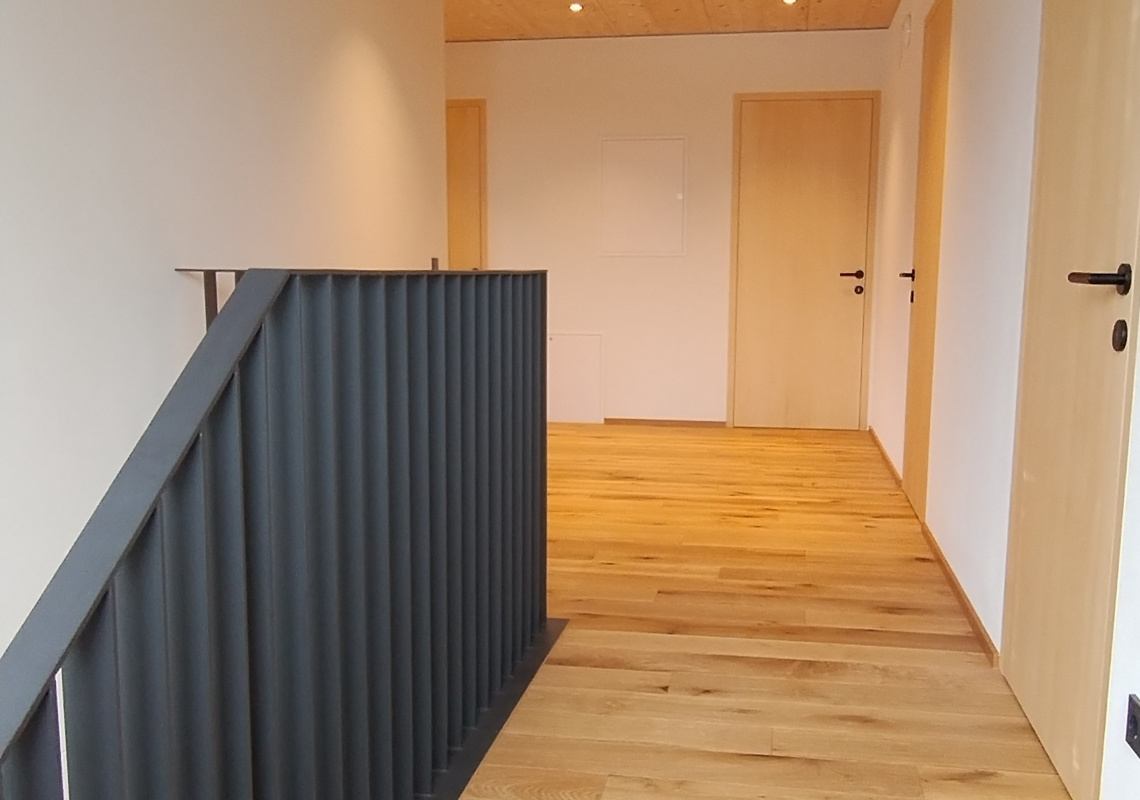 Im Obergeschoss nach der Sanierung, Holzböden und Decke mit modernem Treppengeländer
